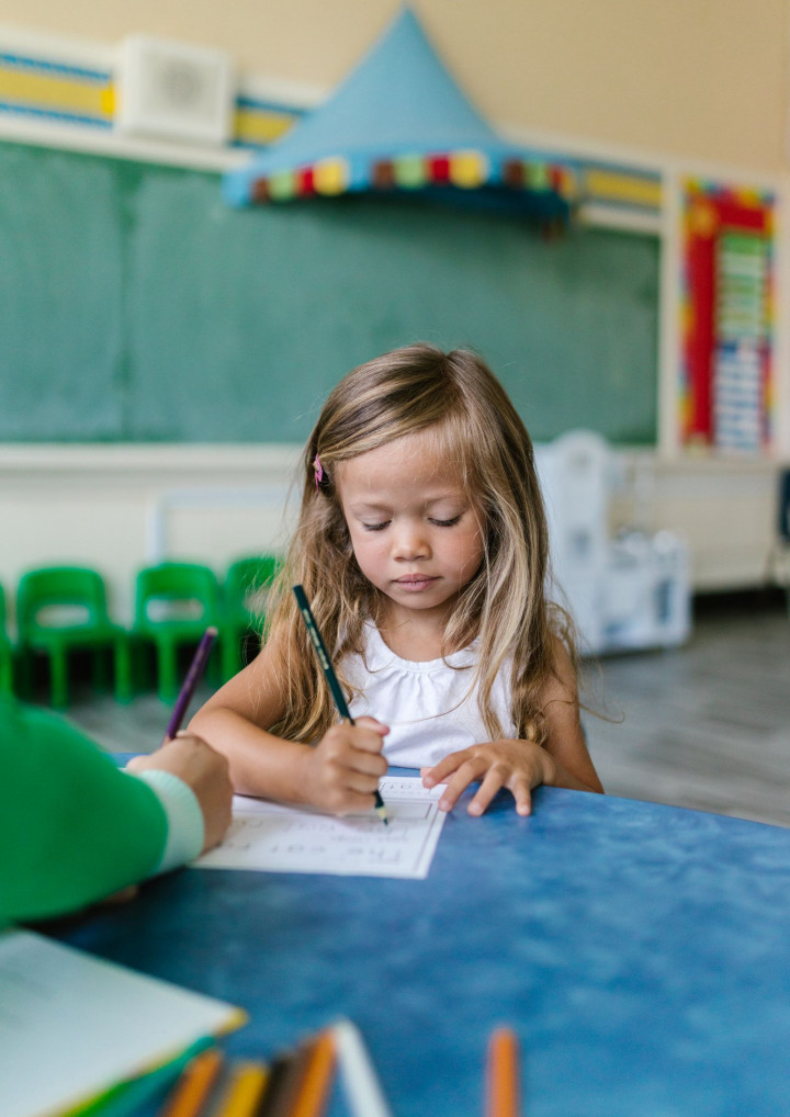 Kind schreibt auf Papier in einem Klassenzimmer