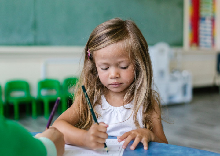 Kind schreibt auf Papier in einem Klassenzimmer